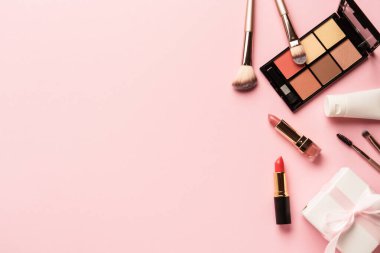 Makyaj ürünleri pembeye yatar. Göz farı, fosforlu kalem, krem, ruj ve kozmetik fırçalar..