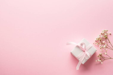 Pembe düz zemin. Beyaz çiçekli hediye kutusu..