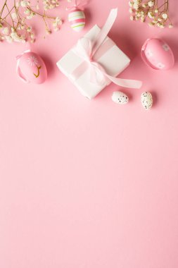 Pembe arka planda Paskalya yumurtaları. Renkli yumurtalar, çiçekler, hediye kutusu ve tatil süslemeleri. Kopyalama alanı olan düz.