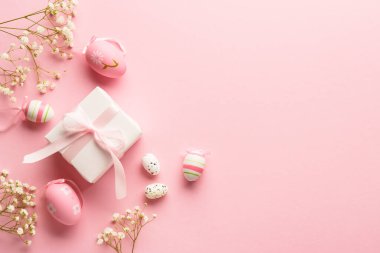 Pembe arka planda Paskalya yumurtaları. Renkli yumurtalar, çiçekler, hediye kutusu ve tatil süslemeleri. Kopyalama alanı olan düz.