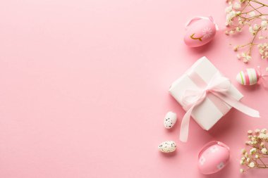 Pembe arka planda Paskalya yumurtaları. Renkli yumurtalar, çiçekler, hediye kutusu ve tatil süslemeleri. Kopyalama alanı olan düz.
