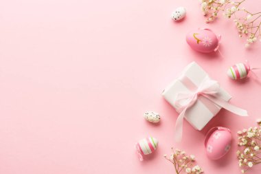 Pembe arka planda Paskalya yumurtaları. Renkli yumurtalar, çiçekler, hediye kutusu ve tatil süslemeleri. Kopyalama alanı olan düz.