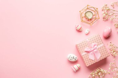 Pembe arka planda Paskalya kompozisyonu. Paskalya yumurtaları, çiçekler, hediye kutusu. Kopyalama alanı olan düz.