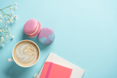 Bir fincan kahve, badem kurabiyesi ve mavi arka planda çiçek. Kopyalama alanı olan düz.