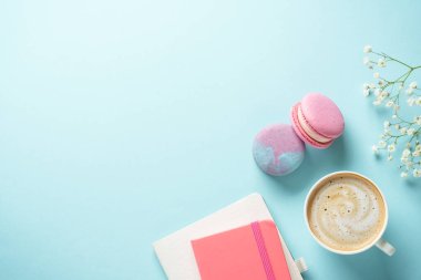 Bir fincan kahve, badem kurabiyesi ve mavi arka planda çiçek. Kopyalama alanı olan düz.