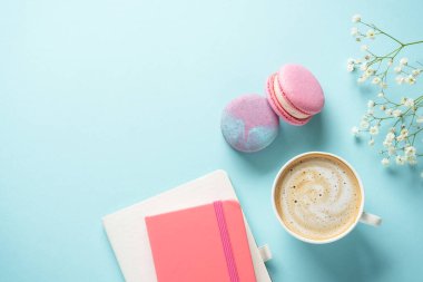 Bir fincan kahve, badem kurabiyesi ve mavi arka planda çiçek. Kopyalama alanı olan düz.