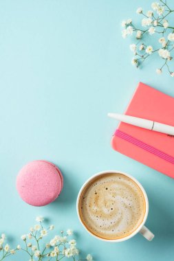 Bir fincan kahve, badem kurabiyesi ve mavi arka planda çiçek. Kopyalama alanı olan üst görünüm.