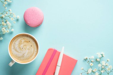 Bir fincan kahve, badem kurabiyesi ve mavi arka planda çiçek. Kopyalama alanı olan üst görünüm.