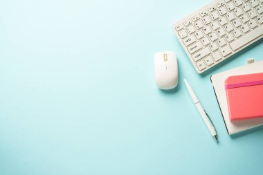 Klavyeli ofis masası, mavi arka planda defter ve kalem. Kopyalama alanı olan düz.