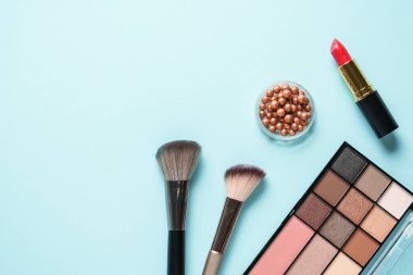 Maviye makyaj ürünleri. Kozmetik palet, fırçalar, rujlar. Üst görünüm.