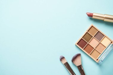 Maviye makyaj ürünleri. Kozmetik palet, fırçalar, rujlar. Üst görünüm.