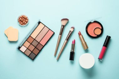 Maviye makyaj ürünleri. Kozmetik palet, fırçalar, rujlar. Üst görünüm.