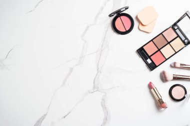Beyaz mermer arka planda ürünler uydur. Kozmetik palet, fırçalar ve rujlar. Kopyalama alanı olan üst görünüm.