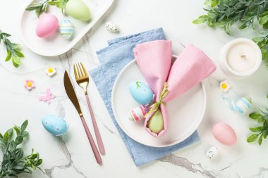 Beyaz arka planda Paskalya sofrası. Beyaz tabak, çatal bıçak takımı ve paskalya süslemeleri. Düz yatıyordu.