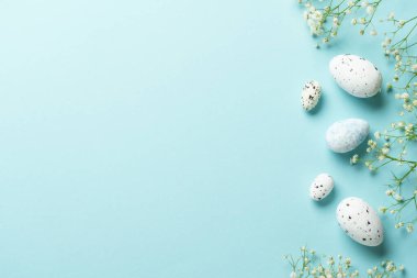 Yumurta ve çiçekli Paskalya arkaplanı. Mavi arka planda düz uzandı.