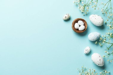 Yumurta ve çiçekli Paskalya arkaplanı. Mavi arka planda düz uzandı.