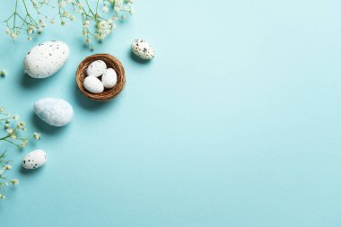 Yumurta ve çiçekli Paskalya arkaplanı. Mavi arka planda düz uzandı.