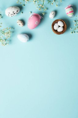 Paskalya yumurtaları. Paskalya bayramı kompozisyonu, güzel süslemeler ve çiçekler. Mavi arkaplanda üst görünüm.