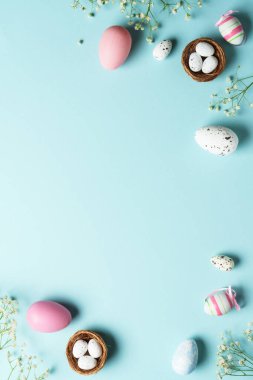 Paskalya yumurtaları. Paskalya bayramı kompozisyonu, güzel süslemeler ve çiçekler. Mavi arkaplanda üst görünüm.