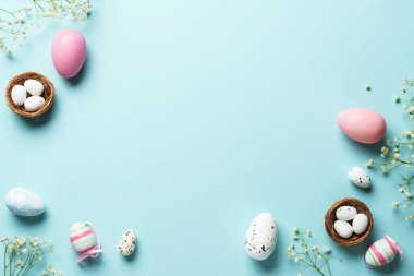Paskalya yumurtaları, dekorasyonlar ve çiçeklerle sıcak Paskalya kompozisyonu. Üstteki görünüm mavi arkaplan ve kopyalama alanı.