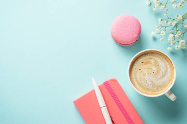 Ofis çalışma alanı düzlüğü. Kahve, badem kurabiyesi ve mavi arka planda çiçek..