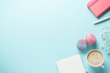 Bir fincan kahve, badem kurabiyesi ve mavi arka planda çiçek. Kopyalama alanı olan üst görünüm.