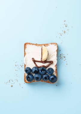 Üzerinde komik resimler olan açık bir sandviç. Yabanmersini ve çikolata ezmeli tost..