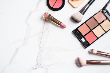 Ürünleri beyaz arka planda uydur. Kozmetik palet, fırçalar ve rujlar. Kopyalama alanı olan üst görünüm.