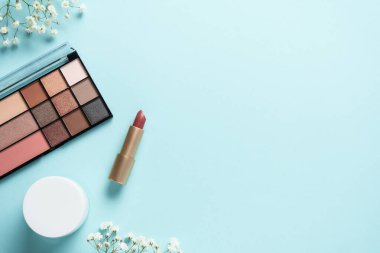 Kozmetik palet, krem, ruj ve mavi üzerine beyaz çiçekler..