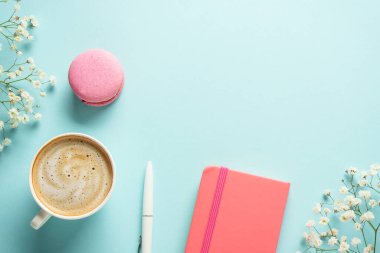 Ofis çalışma alanı düzlüğü. Kahve, badem kurabiyesi ve mavi arka planda çiçek..