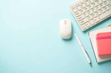 Klavyeli ofis masası, mavi arka planda defter ve kalem. Kopyalama alanı olan düz.