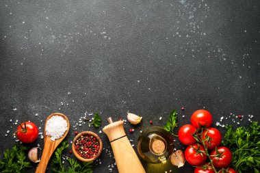 Siyah taş masadaki sağlıklı yemek geçmişi. Organik sebzeler, zeytinyağı, otlar ve baharatlar. Kopyalama alanı olan üst görünüm.