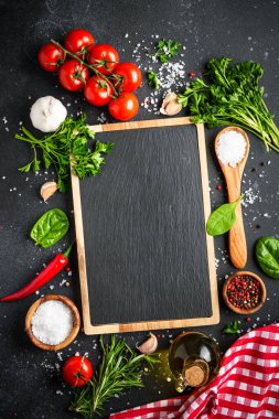 Siyah taş pişirme arka planı. Baharat ve sebze. Kopyalama alanı olan üst görünüm, dikey resim.