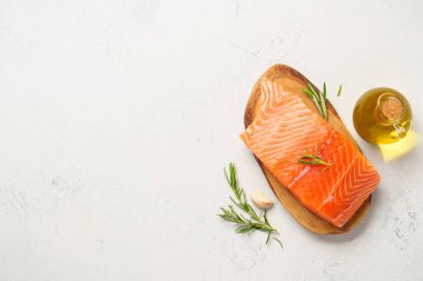 Çiğ somon balığı, otlu ve zeytinyağlı. Beyaz arkaplanda kopyalama alanı olan üst görünüm.