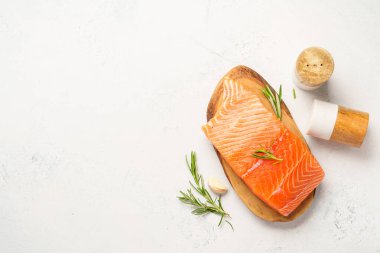 Çiğ somon balığı, otlu ve zeytinyağlı. Beyaz arkaplanda kopyalama alanı olan üst görünüm.