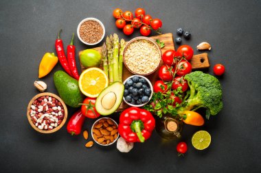 Siyah arka planda sağlıklı yiyecek çeşitleri. Taze sebze, tahıl, yaprak ve fındık. Üst görünüm.