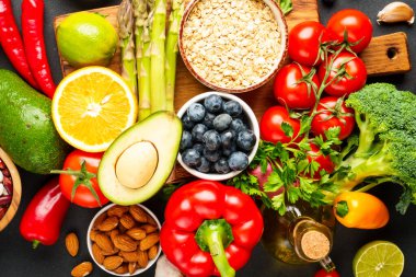 Siyah arka planda sağlıklı yiyecek çeşitleri. Taze sebze, tahıl, yaprak ve fındık. Üst görünüm.