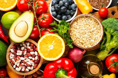 Siyah arka planda sağlıklı yiyecek çeşitleri. Taze sebze, tahıl, yaprak ve fındık. Üst görünüm.