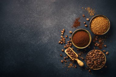 Roasted coffee beans, ground coffee and instant coffee in bowls at dark background. Flat lay image.