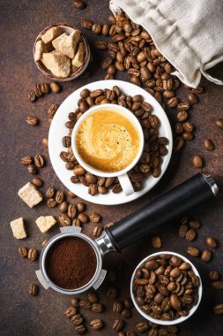 Bir fincan kahve, kavrulmuş kahve çekirdekleri ve koyu masada filtre tutacağı. Üst görünüm, kapat, dikey görüntü.