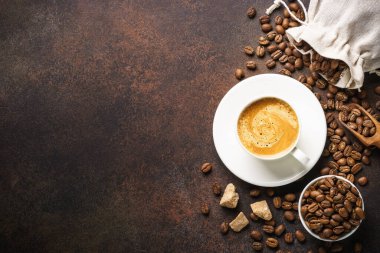 Bir fincan kahve, kavrulmuş kahve çekirdeği ve koyu masada kahverengi şekerli filtre tutacağı. Üst görünüm
