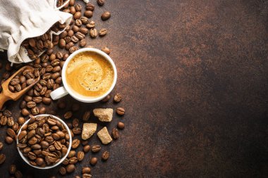 Bir fincan kahve, kavrulmuş kahve çekirdeği ve koyu masada kahverengi şekerli filtre tutacağı. Üst görünüm