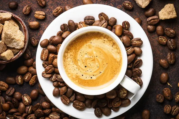 Bir fincan kahve, kavrulmuş kahve çekirdekleri ve koyu masada filtre tutacağı. Üst görünüm