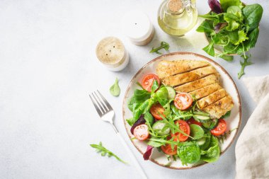 Green salad with chicken fillet on white. Diet food, healthy nutrition. Top view with copy space.