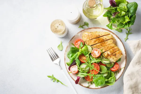 Green salad with chicken fillet on white. Diet food, healthy nutrition. Top view with copy space.
