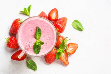 Çilekli smoothie ya da beyaz masada bardakta milkshake. Kopyalama alanı olan üst görünüm.