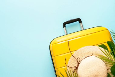 Yaz tatili, seyahat konsepti. Çanta, şapka ve palmiye yaprakları mavi arka planda. Metin için boşluk ile düz uzandı.