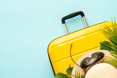 Çanta, şapka ve palmiye yaprakları mavi arka planda. Metin için boşluk ile düz uzandı.