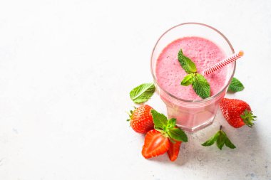 Çilekli smoothie ya da beyaz masada bardakta milkshake. Kopyalama alanı olan düz resim.