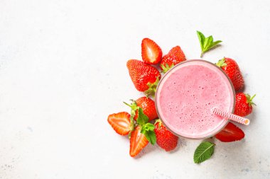 Çilekli smoothie ya da beyaz masada bardakta milkshake. Kopyalama alanı olan düz resim.